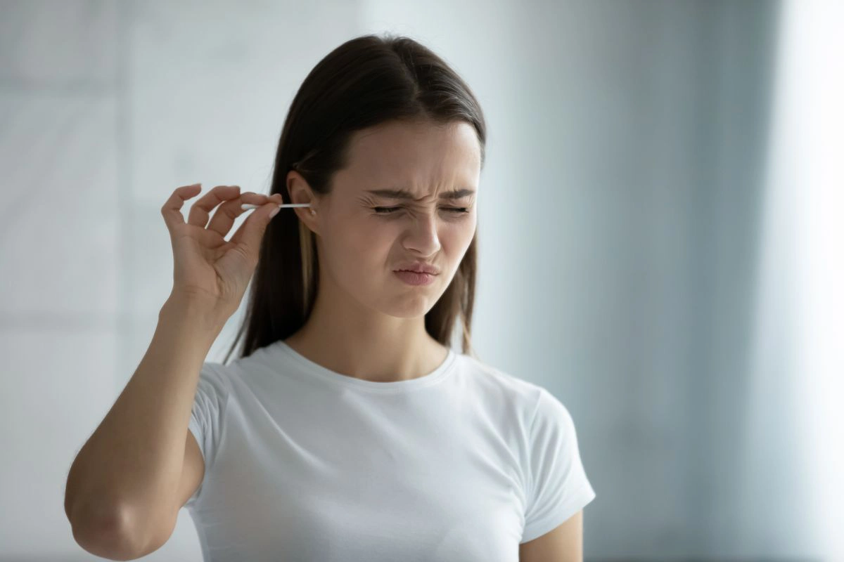 Woman cleaning ear with cotton bud